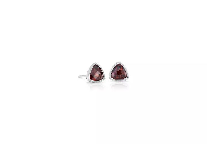 A pair of January birthstone earrings featuring bezel-set, trillion-cut garnets embellished with a milgrain halo